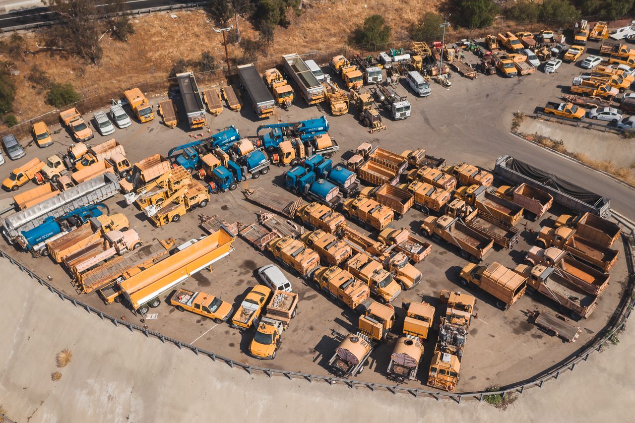 About Drone shot of a parking lot filled with industrial vehicles, showcasing an organized layout from above.